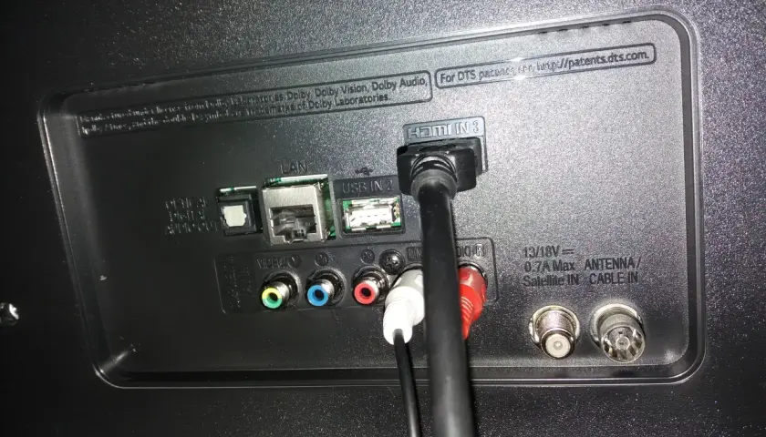 Tył telewizora z podłączonymi kablami HDMI, USB, LAN i audio.